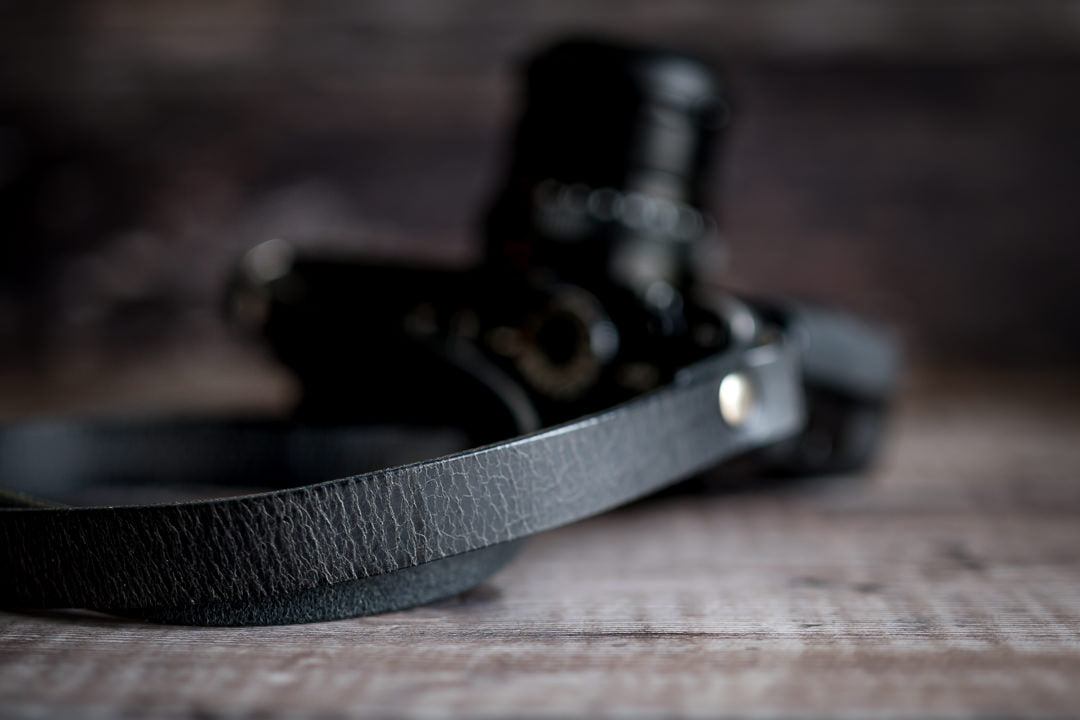 Close-up of crackle finish texture on antique black leather camera strap